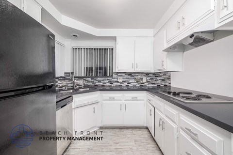 A kitchen with a black refrigerator and white cabinets.