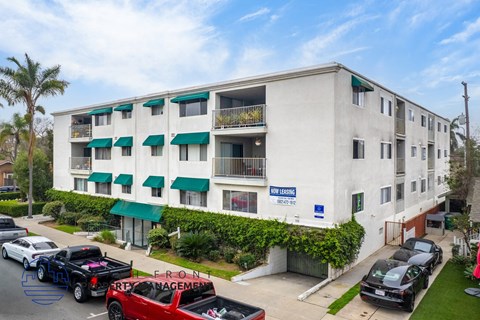 A multi-story apartment building with a blue sign that says "The Leasing Service" on the front.