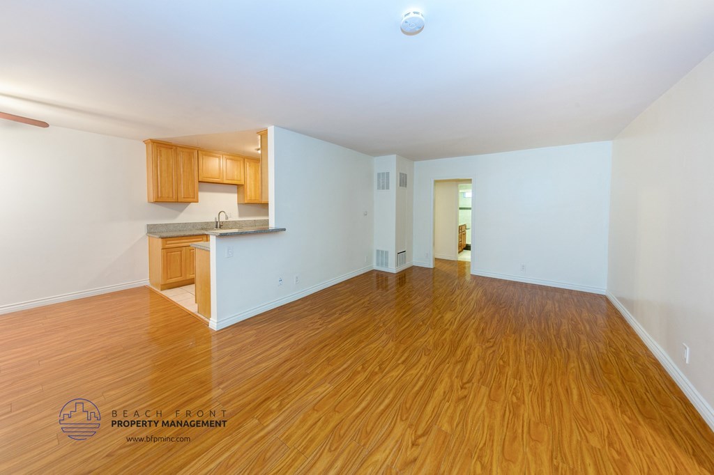 the living room and kitchen of an empty house with wood flooring