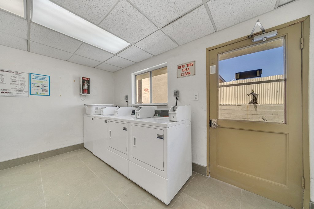 a utility room with washing machines and a door to a laundry room with two sinks