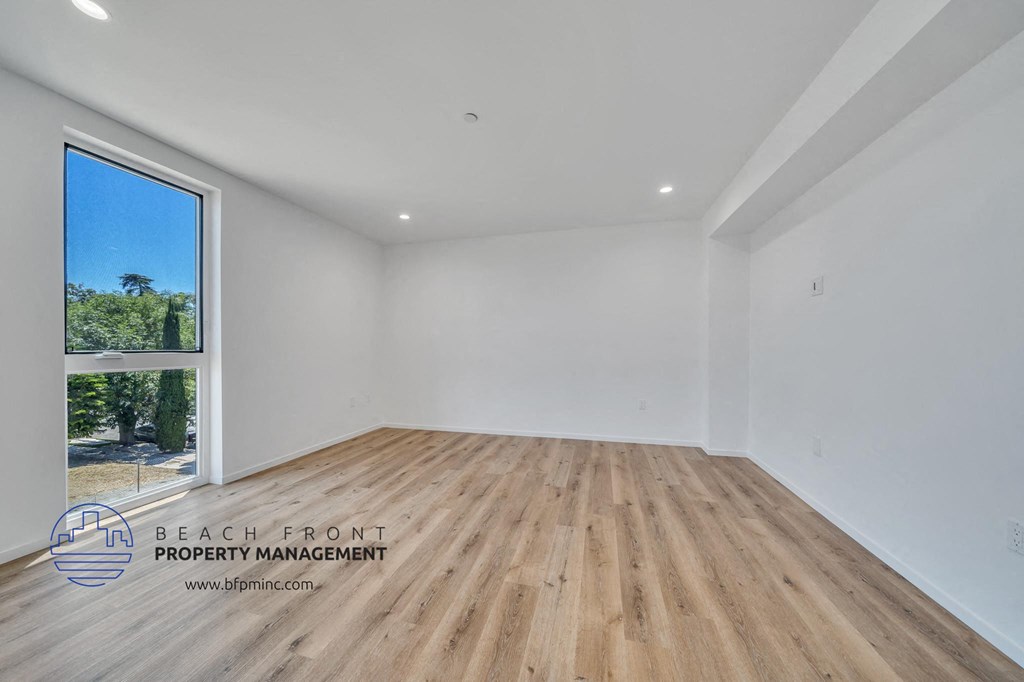 a white room with wood flooring and a large window