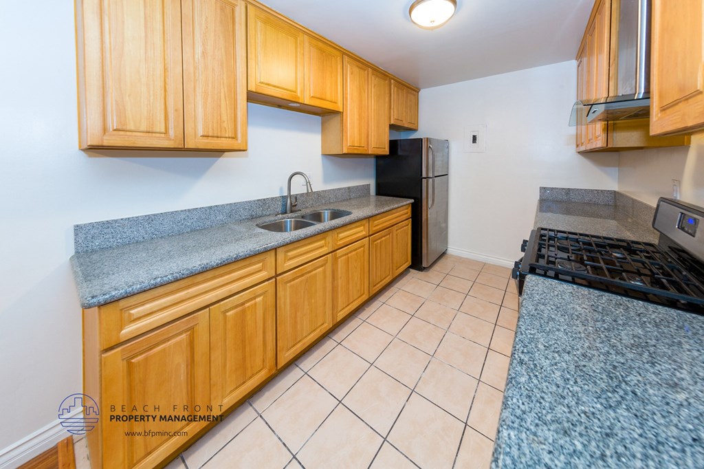 a kitchen with wood cabinets and granite counter tops and a black refrigerator