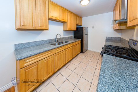 a kitchen with wood cabinets and granite counter tops and a black refrigerator