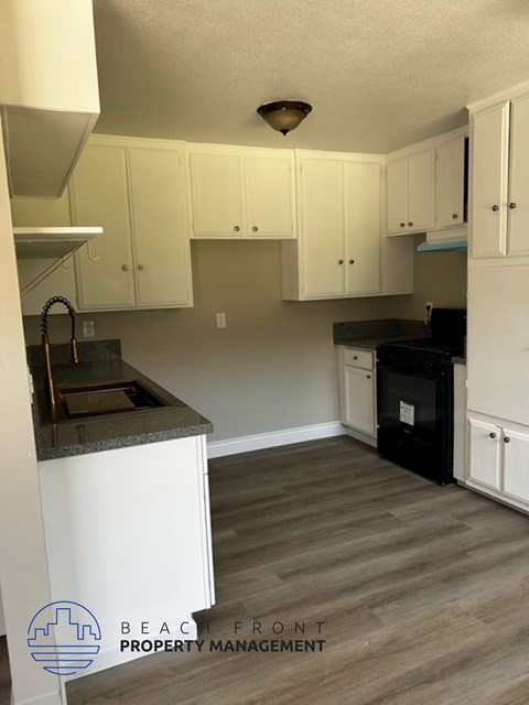 A kitchen with white cabinets and a black oven.
