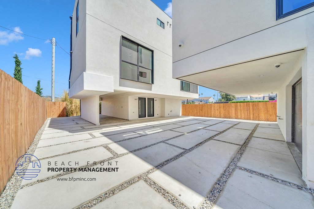 a patio with a white house and a wooden fence