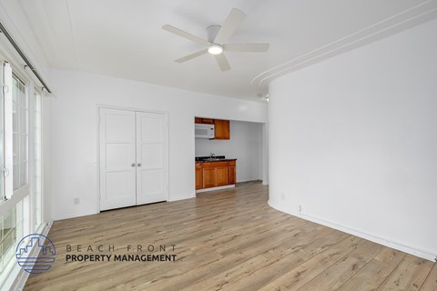 A spacious room with wooden flooring and a ceiling fan.