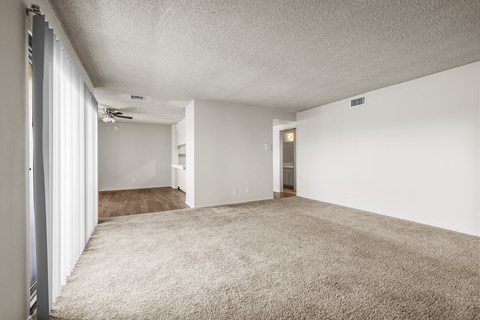A spacious room with carpeted floor and white walls.