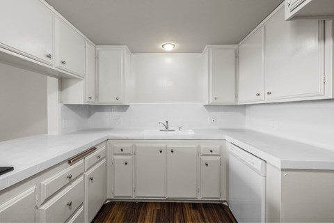 A kitchen with white cabinets and a white countertop.