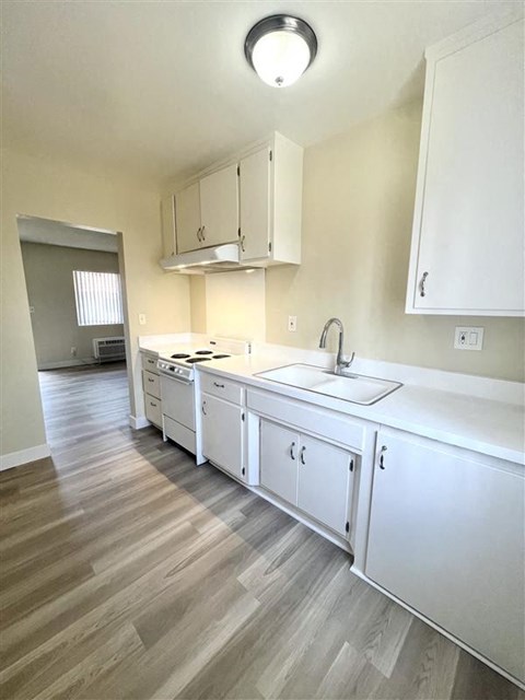 A kitchen with white cabinets and a wooden floor.
