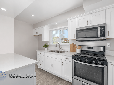 A kitchen with white cabinets and a stove top oven.