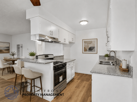 A modern kitchen with white cabinets and a marble countertop.