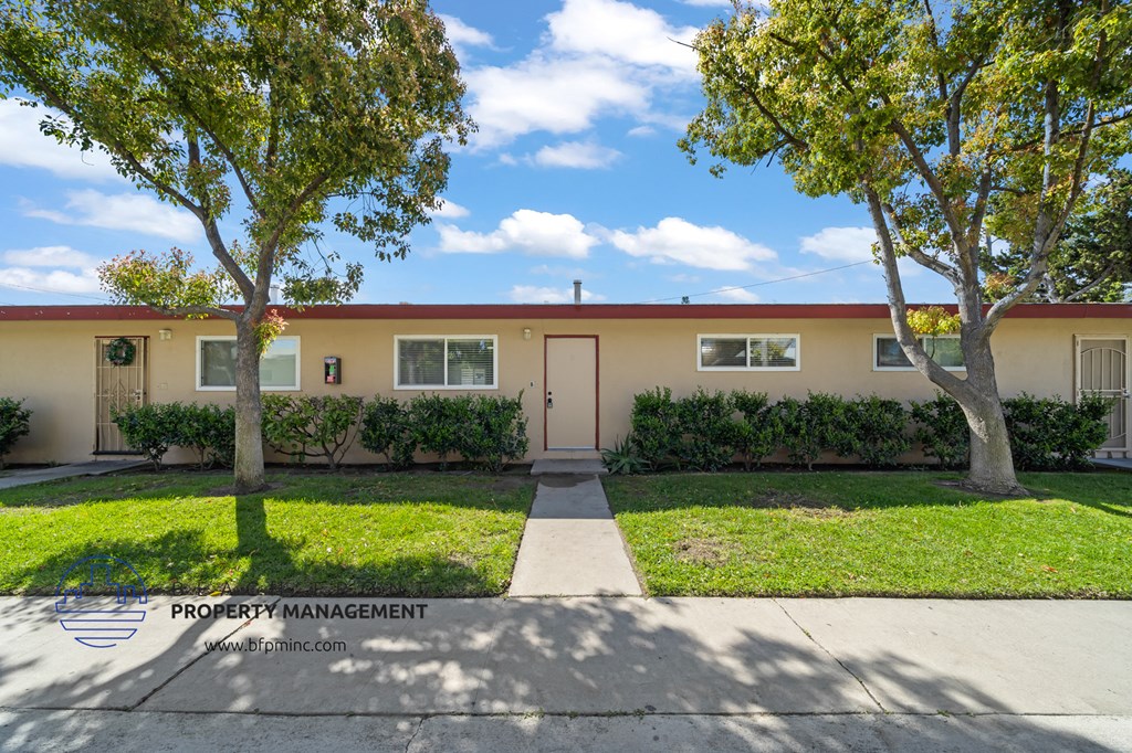 a home with a sidewalk and trees in front of it