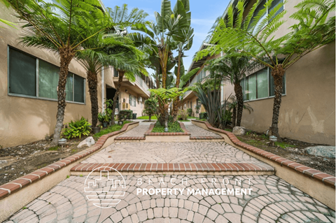 a walkway with palm trees in front of a building