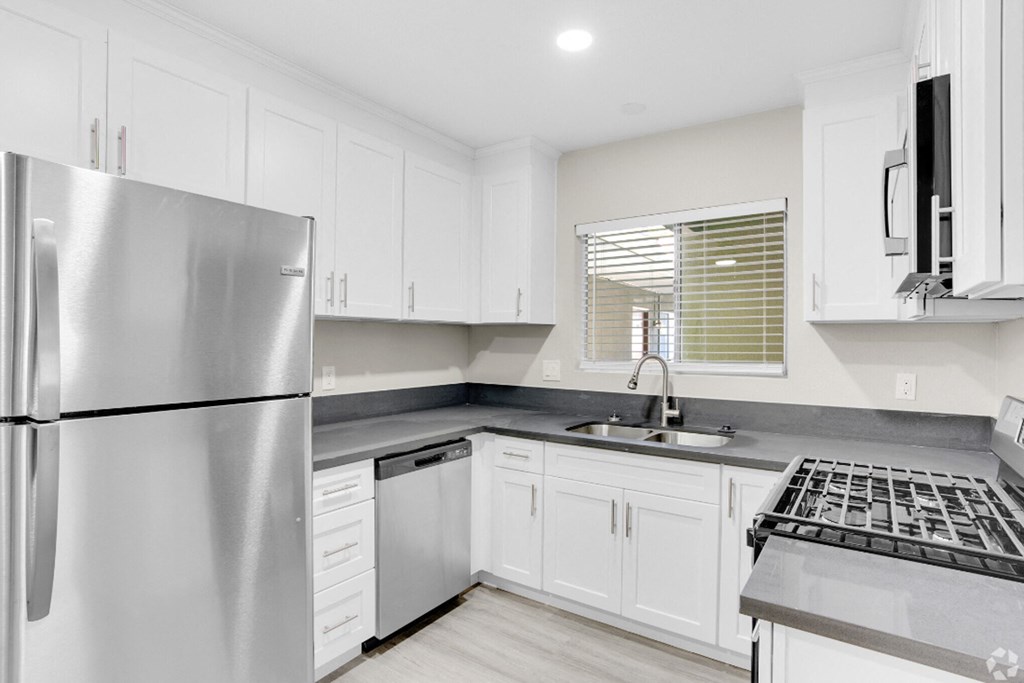 a white kitchen with stainless steel appliances and white cabinets