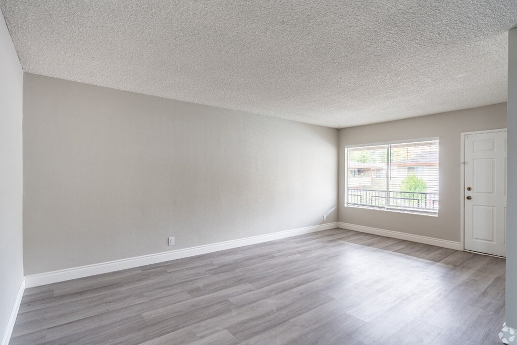 an empty living room with wood floors and a window