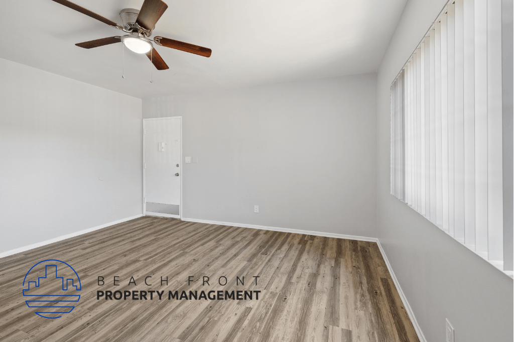 the living room of an apartment with wood flooring and a ceiling fan