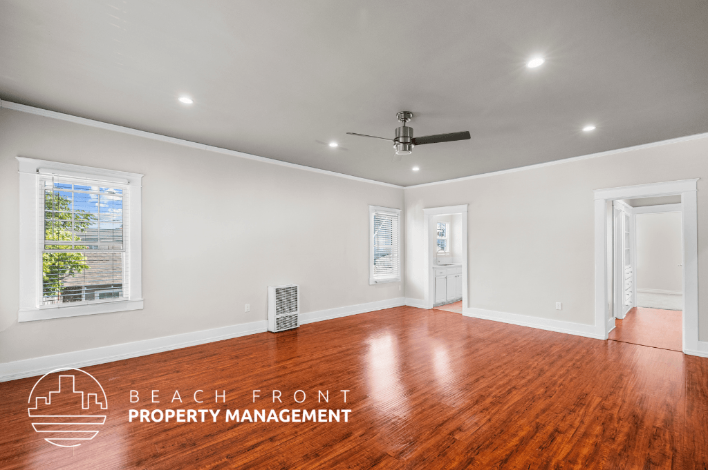 an empty living room with wood floors and a ceiling fan