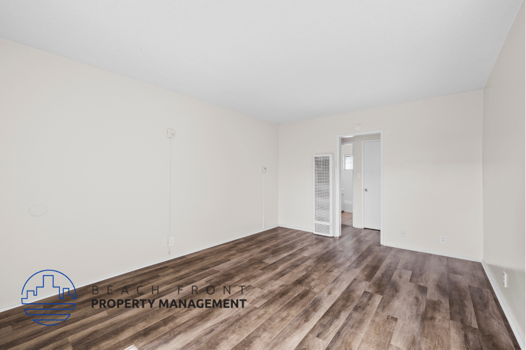 the spacious living room with wood flooring and white walls