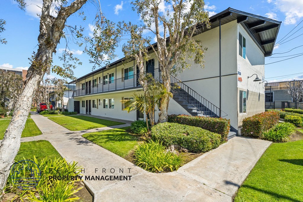 a large white building with a sidewalk and trees in front of it