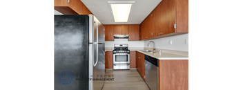 A kitchen with a black fridge and wooden cabinets.