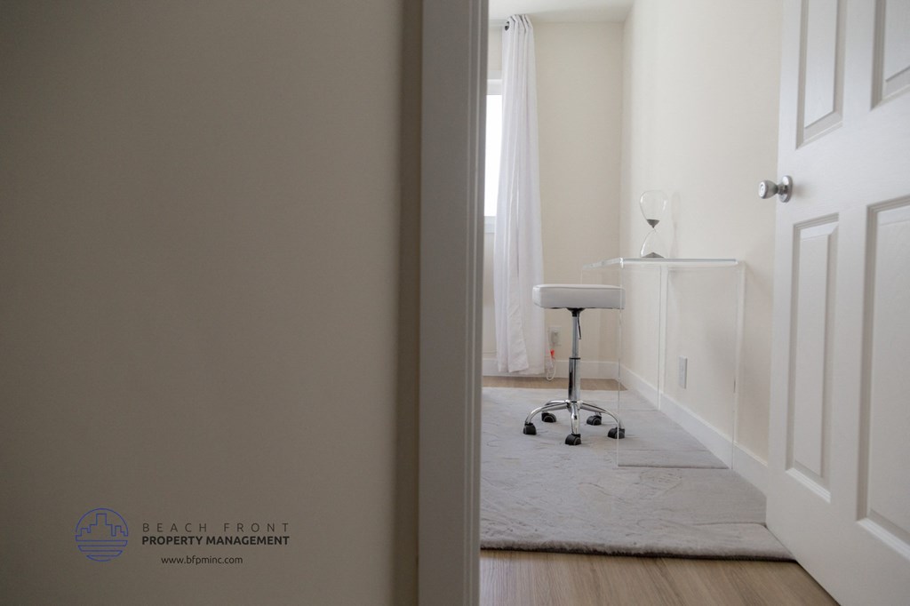 A hallway with a white chair and a white rug.