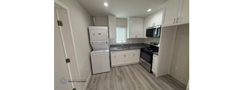 A kitchen with white cabinets and a white fridge.