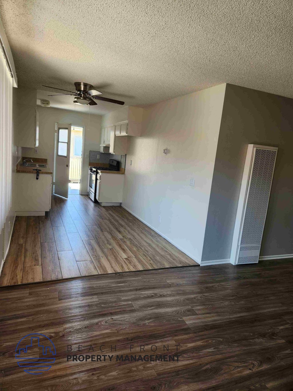 A spacious room with wooden floors and a ceiling fan.