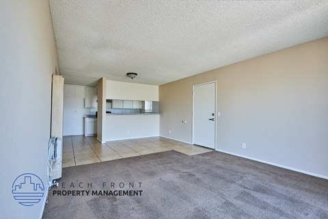 A spacious room with a carpeted floor and a logo for Beach Front Property Management in the bottom left corner.