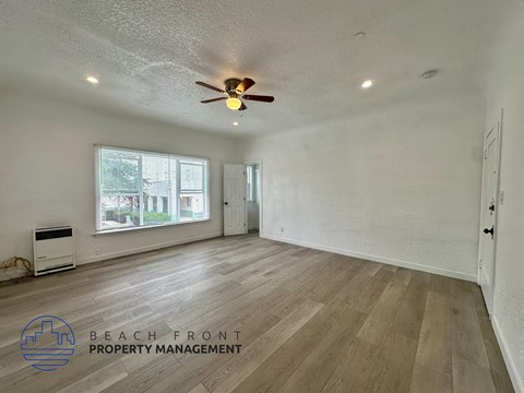 A spacious room with wooden flooring and a ceiling fan.