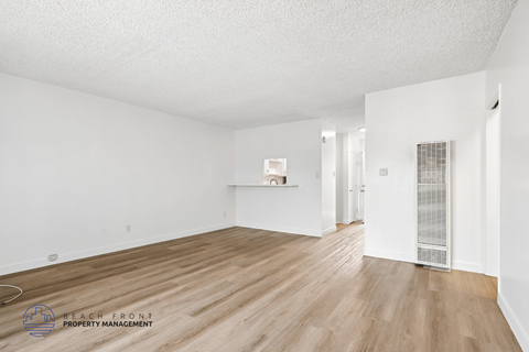 A spacious room with wooden flooring and white walls.