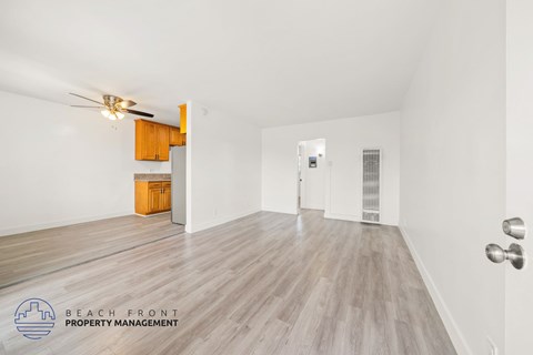 A spacious room with wooden flooring and a ceiling fan.