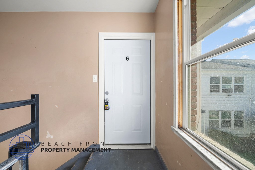 A white door with a black handle is in a room with a window.
