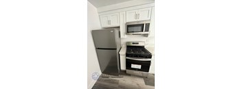 A kitchen with a stainless steel refrigerator, microwave, and stove.