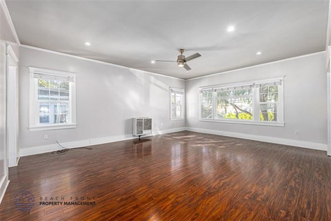 A spacious room with wooden floors and a ceiling fan.