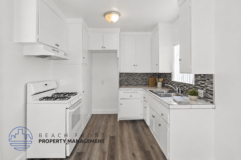 A kitchen with white cabinets and a wooden floor.