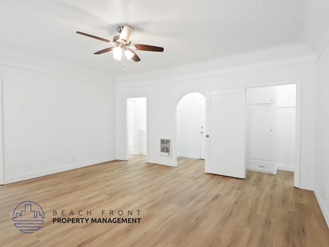 A spacious room with a ceiling fan and wooden flooring.
