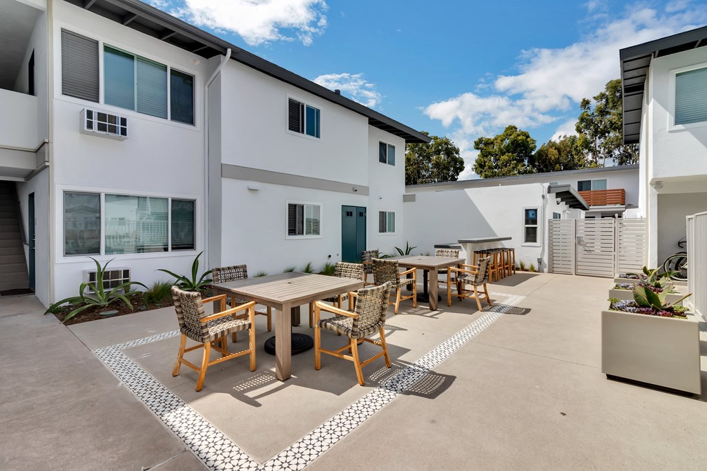 A patio with a table and chairs is surrounded by a white and black patterned rug.