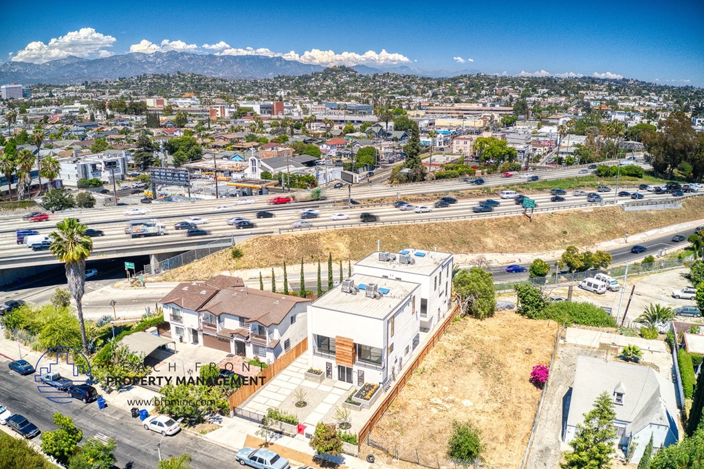 an aerial view of a building and a city with cars on the freeway