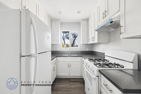 A kitchen with white cabinets and a black countertop.