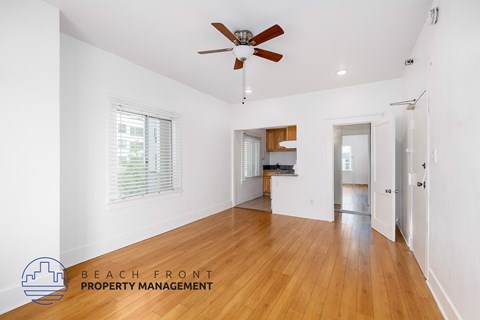 A spacious room with wooden floors and a ceiling fan.