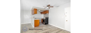 A kitchen area with a white ceiling fan and wooden cabinets.
