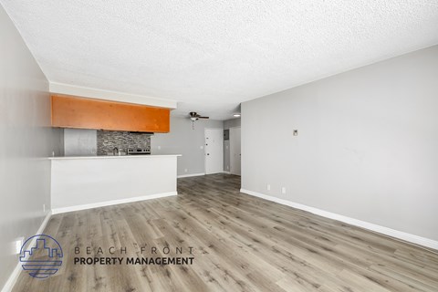 A spacious room with wooden flooring and a fireplace with a white wall and a door in the background.