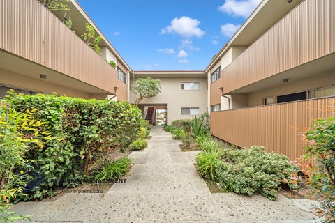 the courtyard of an apartment building with a walkway and plants