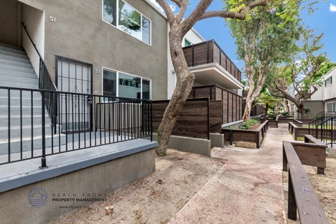 a patio with benches and a building with a fence and trees