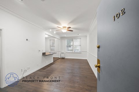 a renovated living room and kitchen with white walls and a ceiling fan