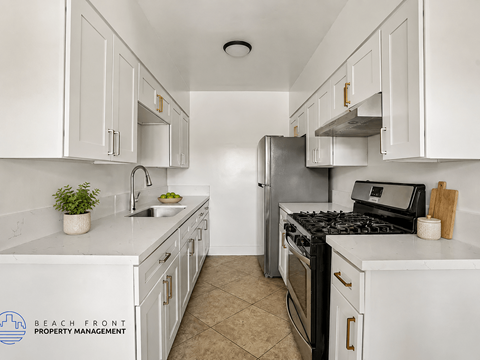 A kitchen with white cabinets and appliances, a sink, and a stove top oven.
