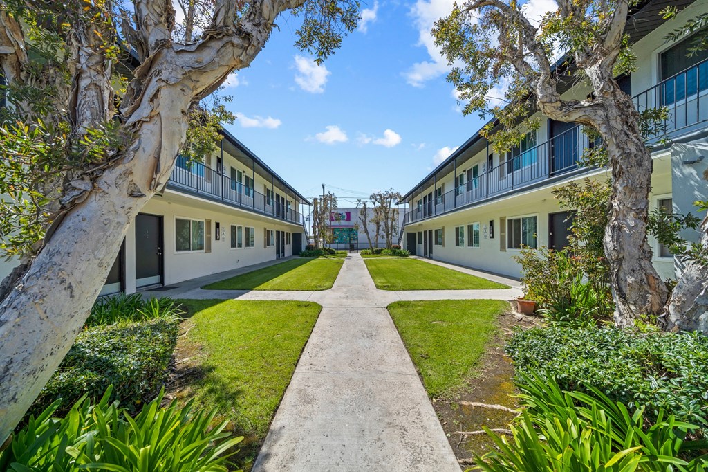 a courtyard between two apartment buildings with grass and trees
