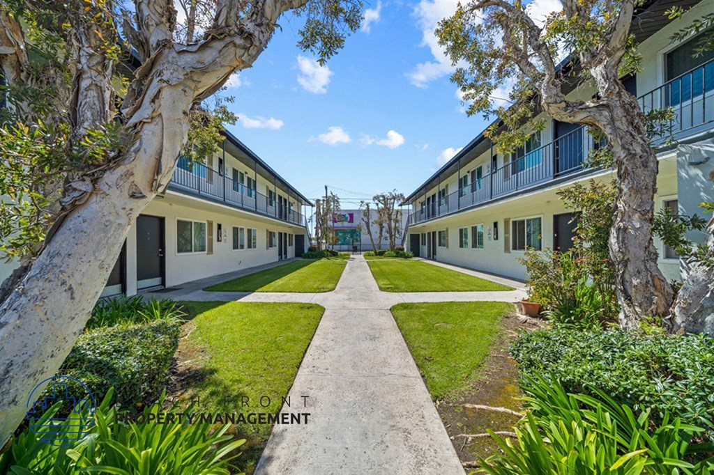 a courtyard between two buildings with grass and trees