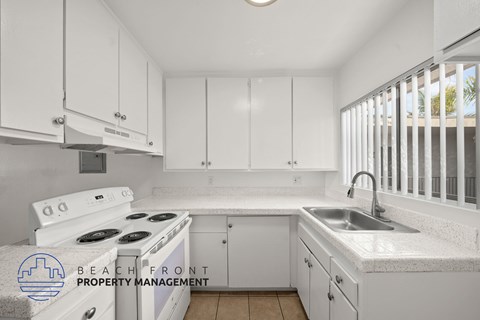 A kitchen with white cabinets and a stove top oven.