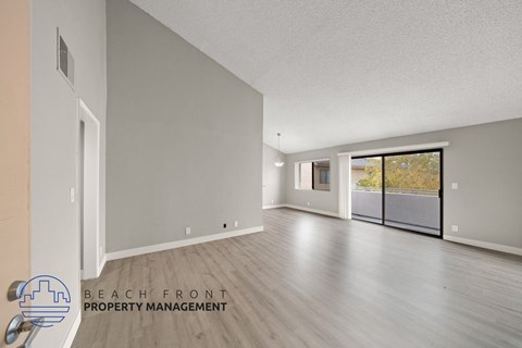 the living room and dining room of an apartment with wood flooring and a balcony
